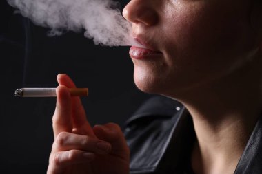 Siyah arka planda sigara içen kadın, yakın plan.