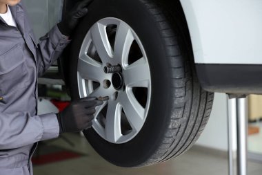 Tamirci araba servisinde lastik değiştiriyor, yakın plan.