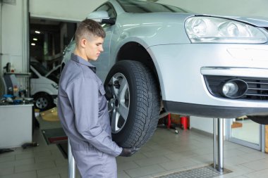 Araba servisinde lastik değiştiren profesyonel bir tamirci.