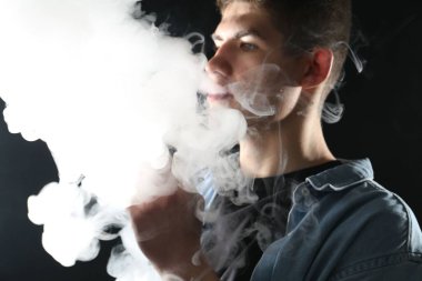 Siyah arkaplanda elektronik sigara içen adam