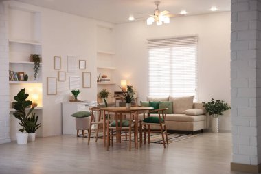 Odada rahat bir kanepe ve sandalyeli şık bir yemek masası. İç tasarım