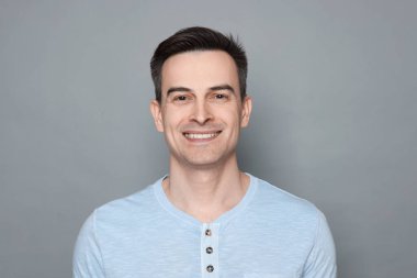 Gri arka planda tıraş olduktan sonra gülümseyen adam