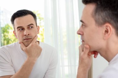 Evde aynanın yanında tıraş olduktan sonra yakışıklı bir adam.