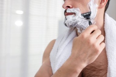Evde tıraş olurken jiletle kesilen adam, yakın plan. Metin için boşluk