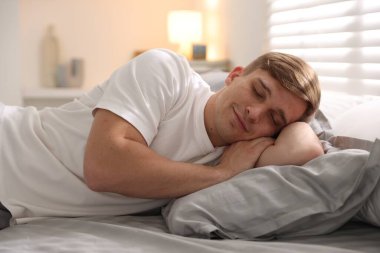 Evdeki yumuşak yatakla yatakta uyuyan genç adam.