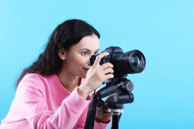 Açık mavi arkaplanda profesyonel video kamerası olan kadın, metin için boşluk