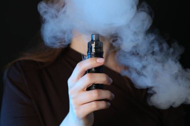 Siyah arkaplanda elektronik sigara içen kadın, yakın plan