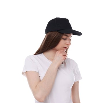 Beyaz arka planda siyah bir şapka takan genç bir kadın.