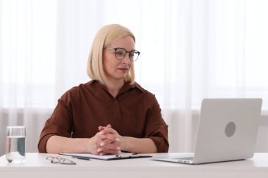 Ofiste dizüstü bilgisayarla çalışan profesyonel bir psikolog.