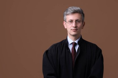Kahverengi arka planda mahkeme elbisesi giymiş bir yargıç. Metin için boşluk