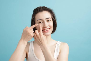 Açık mavi arkaplana kontak lens takan kadın