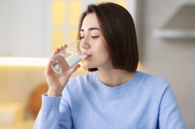 Evinden su içen genç bir kadın.