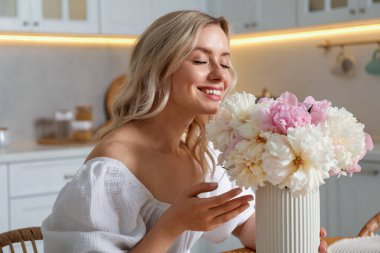 Mutfakta şakayık demeti olan mutlu bir kadın.