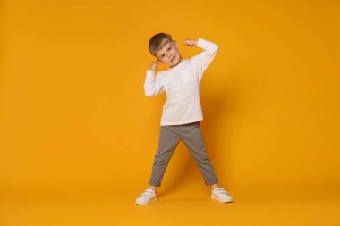 Mutlu küçük çocuk turuncu arka planda dans ediyor