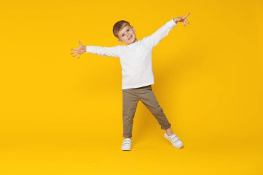 Mutlu küçük çocuk turuncu arka planda dans ediyor