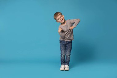 Açık mavi arka planda dans eden mutlu küçük çocuk, mesaj için boşluk