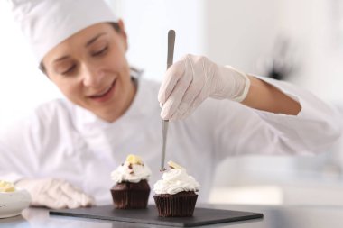 Şekerci, mutfakta bir parça çikolatayla kek dekore ediyor, seçici odaklı.