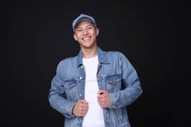 Siyah arka planda şık kot şapkalı genç adam.