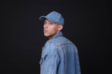 Siyah arka planda şık kot şapkalı genç adam.