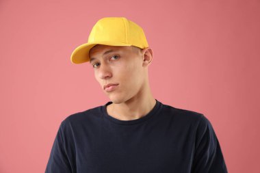 Pembe arka planda şık bir beyzbol şapkası takan genç adam.