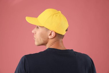 Pembe arka planda şık bir beyzbol şapkası takan genç adam.
