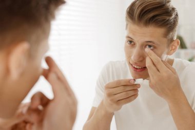 Evdeki aynanın yakınına kontak lens takan adam