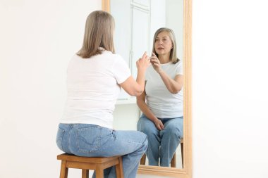 Güzel son sınıf öğrencisi kadın aynada kendine bakıyor.