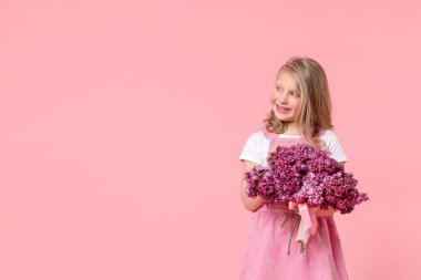 Pembe arka planda bir buket leylak çiçekli küçük kız, mesaj için yer var.