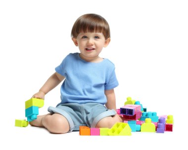 Beyaz arka planda tuğlalarla oynayan sevimli küçük çocuk.