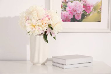 Bir buket güzel şakayık ve kitap kapalı bir masada.