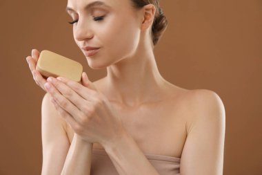 Kahverengi arka planda sabun çubuğu olan güzel kadın, yakın plan.