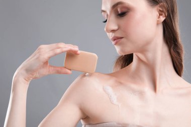 Gri arka planda sabun çubuğu olan güzel kadın, yakın plan.