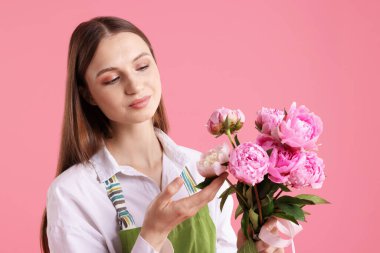 Pembe arka planda güzel şakayıklar olan bir çiçekçi.