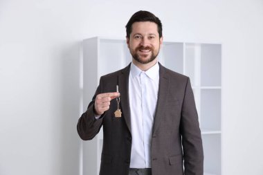 Emlakçının elinde ev şeklindeki anahtarlık var.