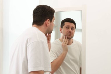 Yakışıklı adam aynada kendine bakıyor.