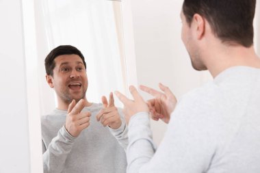 Yakışıklı adam aynada kendine bakıyor.