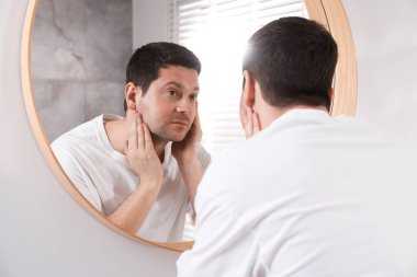 Yakışıklı adam aynada kendine bakıyor.