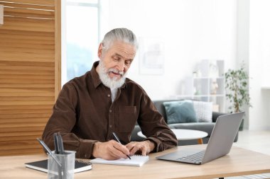 Üst düzey adam içeride masa başında öğrenirken not alıyor. Kendi kendine çalışma.