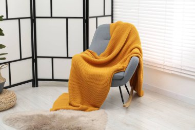 Turuncu yün battaniyeli rahat bir koltuk.