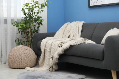 Oturma odasındaki kanepede bej yün battaniye.