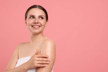 Gülümseyen kadın pembe arka planda koluna vücut ovuşturuyor. Metin için boşluk