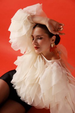 Kırmızı arka planda şık giyinmiş genç bir kadın.