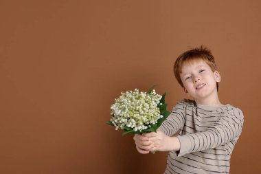 Kahverengi arka planda vadideki güzel çiçekleri olan bir buket çocuk. Metin için boşluk