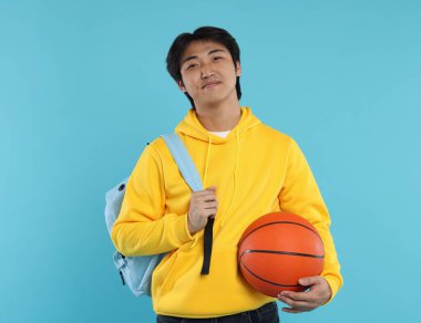 Basketbol topu ve açık mavi arka planda sırt çantası olan öğrenci.