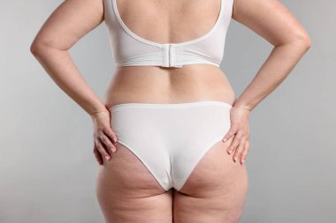 Kilo kaybı. Artı gri arka planda iç çamaşırlı kadın, yakın plan.