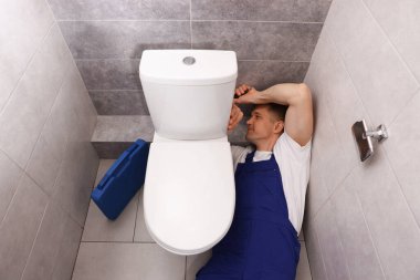 Profesyonel tesisatçı tuvalet deliğini tamir ediyor.