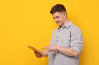 Sarı arka planda modern tablet kullanan bir adam. Metin için boşluk