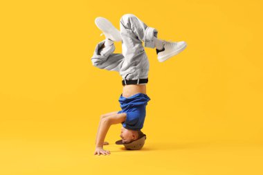 Şık giyinmiş çocuk turuncu arka planda dans ediyor.