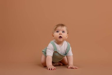 Soluk kahverengi arka planda emekleyen tatlı küçük bebek.