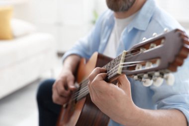 Evde gitar çalan adam, eline odaklan.